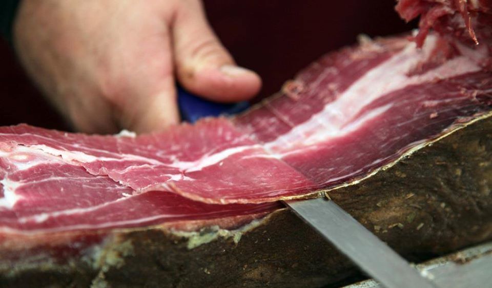 Croatian pršut being thinly sliced for a traditional Pršut i Sir appetizer